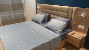 A modern bedroom with a bed, nightstands, and a wooden headboard.
