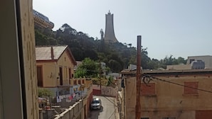 A narrow street with buildings on both sides, a car parked in the middle, and a tower in the distance.