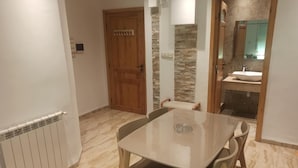 A dining area with a table and chairs, a wooden door, and a stone wall.