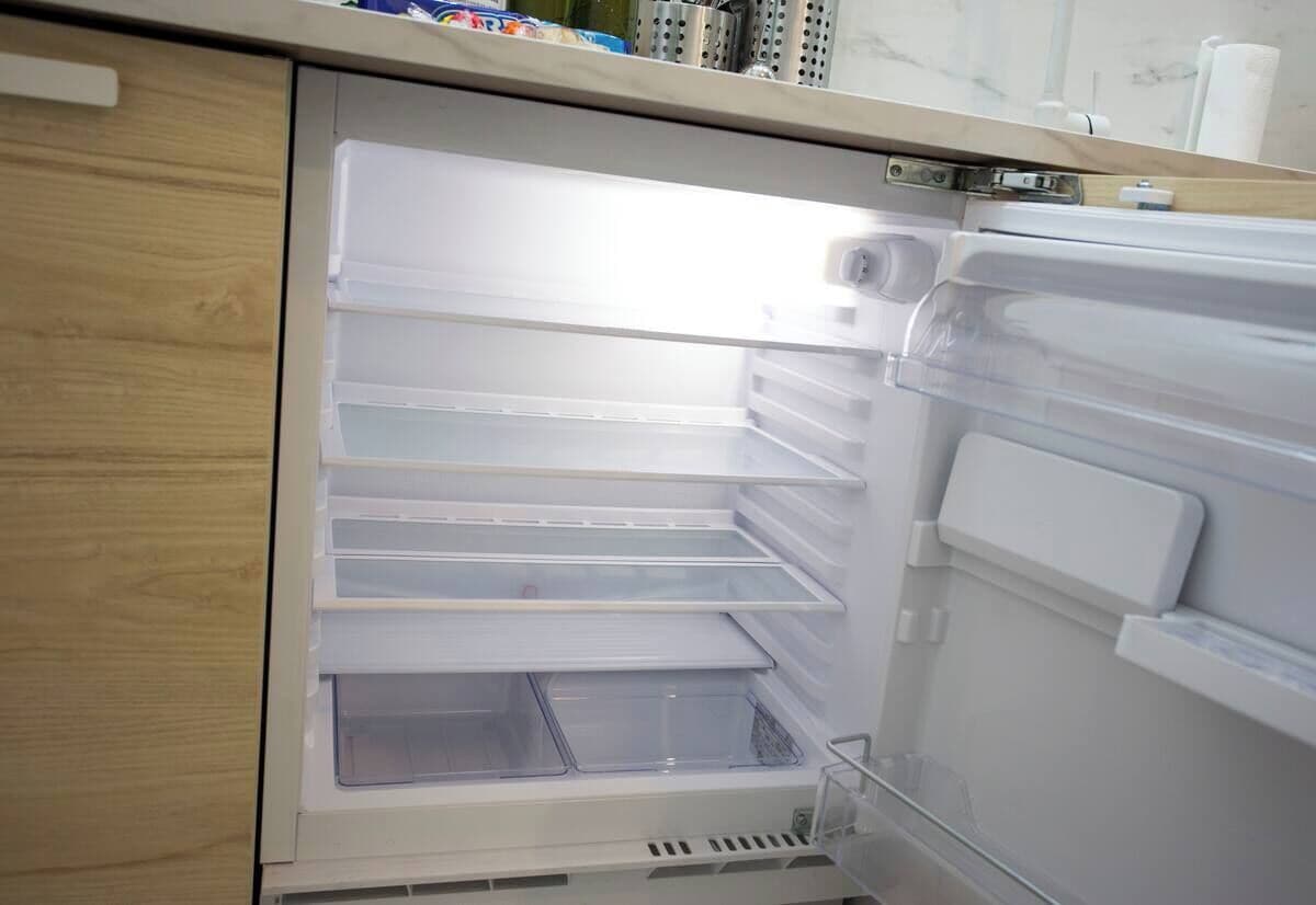 An empty refrigerator with multiple shelves and a freezer compartment.