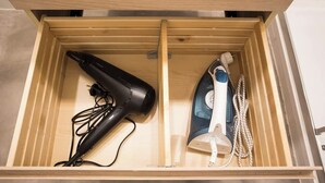 A wooden drawer with a hairdryer and an iron inside.