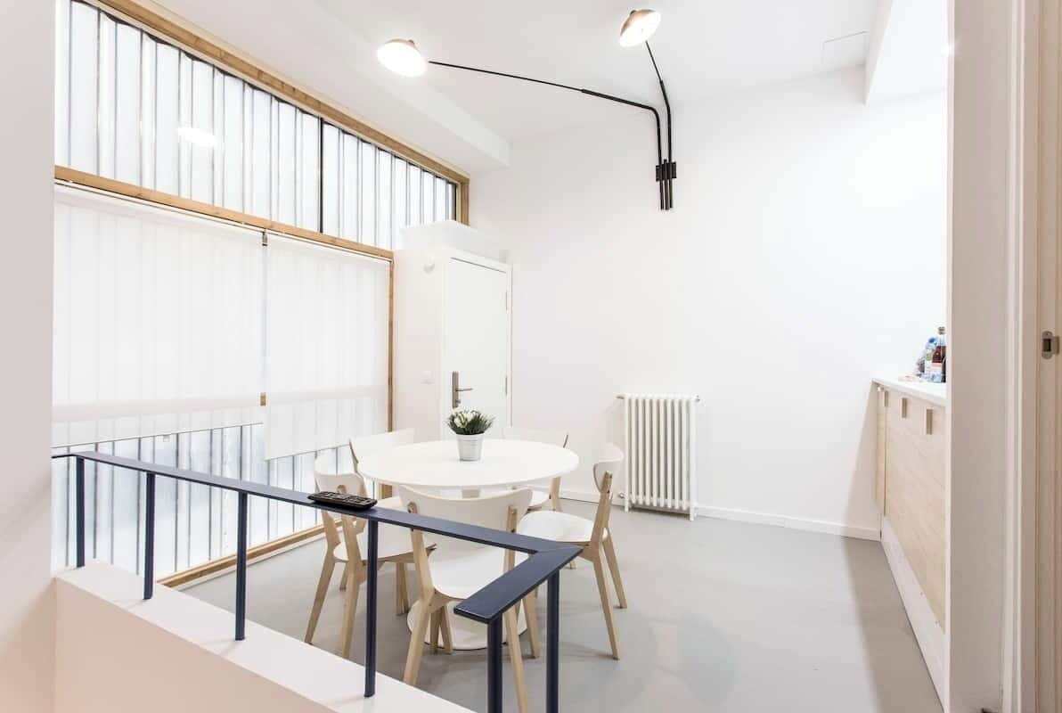 Una habitación moderna y bien iluminada con una mesa de comedor redonda, sillas y una pequeña planta en maceta.