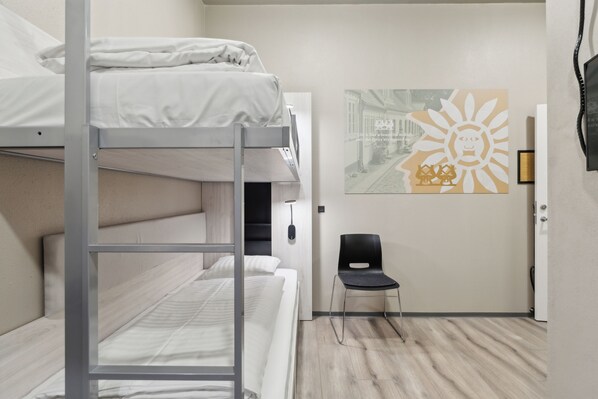 A bunk bed room with a chair and a wall-mounted artwork. - Hotel Fyrtøjet - We give less You save more (Odense)