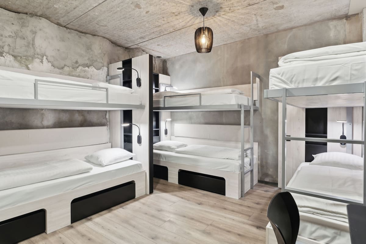 A bunk bed room with a concrete ceiling, a hanging light fixture, and a wooden floor.