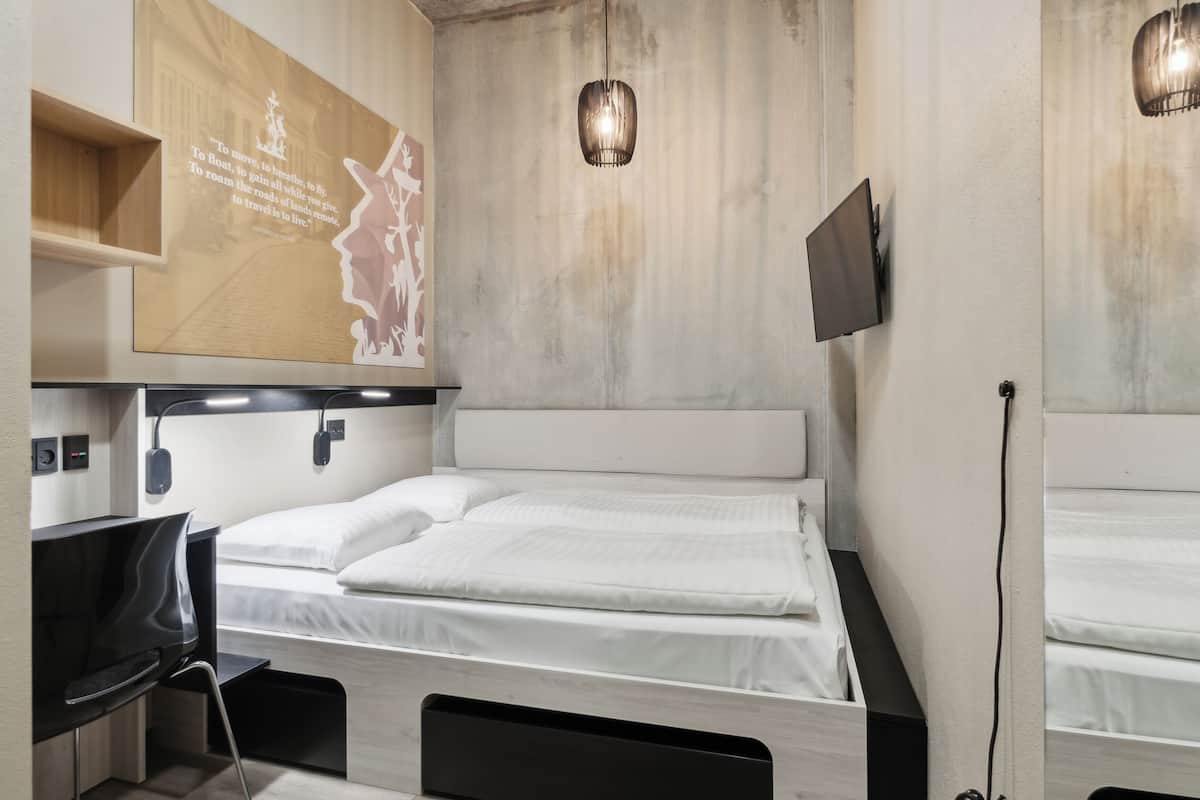 A modern room with a bed, a desk, and a mounted TV.