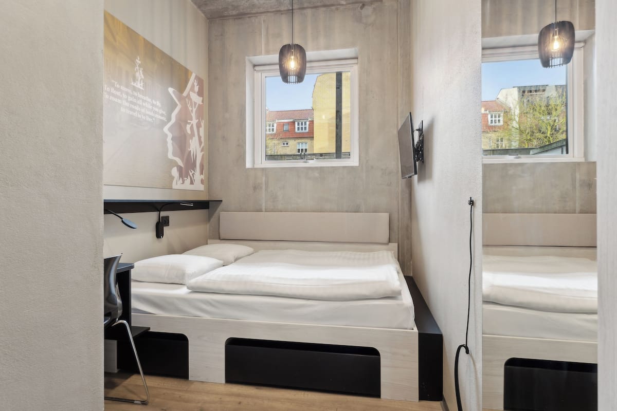 A compact room with a bed, a desk, and a window.
