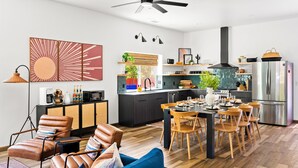 A modern kitchen with a central island, stainless steel appliances, and a dining area with wooden chairs and a blue sofa.