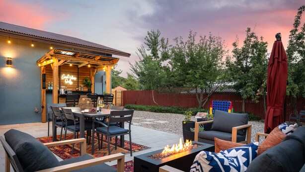 An outdoor patio area with a dining table, chairs, and a fire pit.