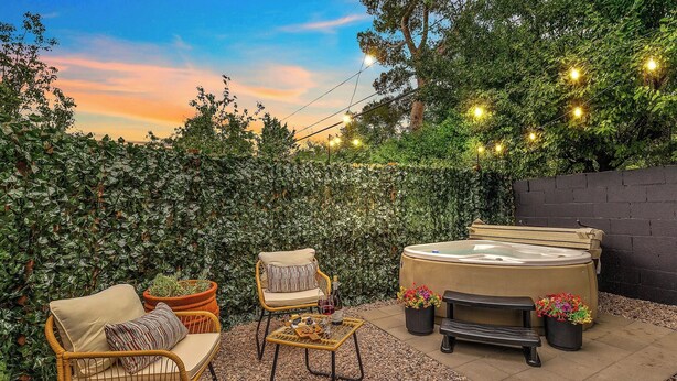 Un espace extérieur aménagé en terrasse, avec des meubles en osier, un jacuzzi et des guirlandes lumineuses.