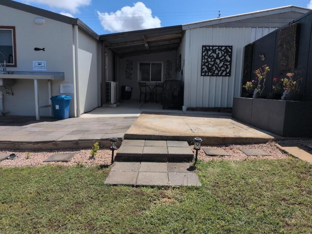 A building with a patio area, a small outdoor seating area, and a trash bin.