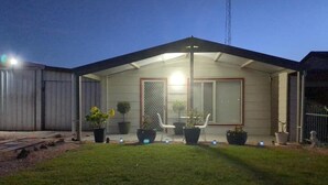 Una casa de una sola planta con un porche cubierto, plantas en macetas y un pequeño jardín.