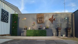 Una pared de concreto con detalles decorativos, incluyendo una cabeza de Buda, peces y estrellas de mar.