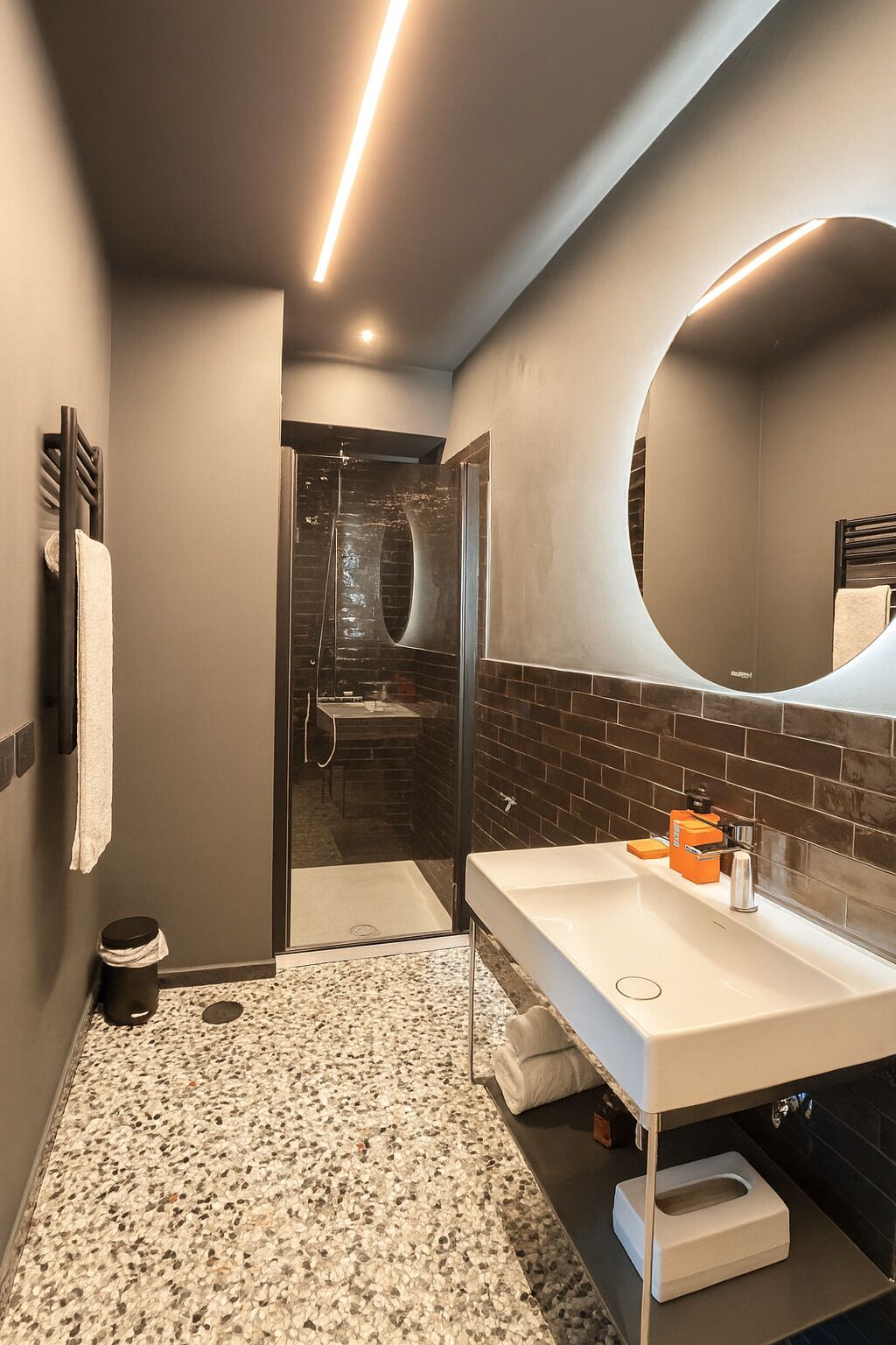 A modern bathroom with a white sink, a large mirror, and a shower area.