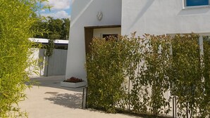 Een modern gebouw met witte muren en een blauw raam, omringd door groen en decoratieve parasols.