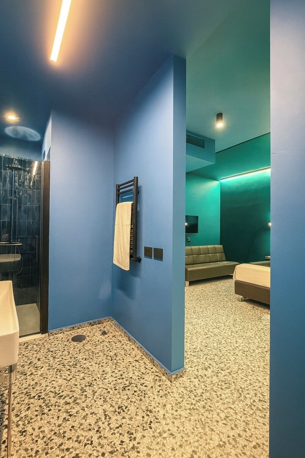 A modern bathroom with a glass shower, a towel rack, and a sink.