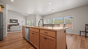 A spacious kitchen with wooden cabinets, a large island, and a built-in dishwasher. - Wasatch Peak Chateau R3 | Ski Snowbasin | Hot Tub (Mountain Green)