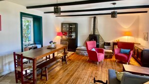 A cozy living room with a wooden floor, a dining table with chairs, a fireplace, and a sofa. - Cosy house 5 min from Poulziourec Beach! (Groix)