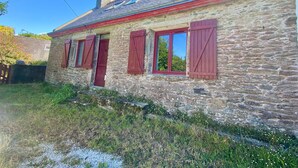 A stone house with red shutters and a sloped roof. - Cosy house 5 min from Poulziourec Beach! (Groix)