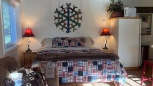 A cozy bedroom with a bed, two bedside lamps, a decorative wall piece, and a small desk area. - Cozy Atelier Studio with views of Baldy (Sun Valley)