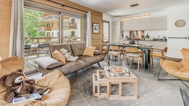 En moderne stue med sofa, sofabord i glas og et spiseområde med stole.
