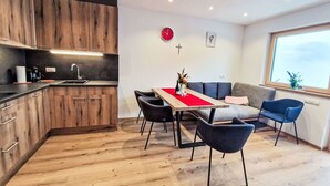 Une cuisine moderne avec des meubles en bois et un coin repas agrémenté d’un chemin de table rouge.