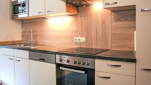 A modern kitchen with a built-in oven, microwave, and stainless steel range hood.
