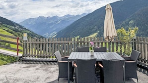 An outdoor seating area with a table and chairs, a wooden fence, and a view of mountains.