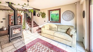 A living room with a sofa, a patterned rug, a staircase, and a wood-burning stove. - Wonderful private villa for 6 guests with WIFI, A/C, TV and terrace (Asti)