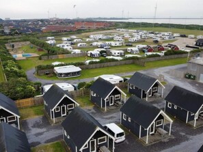 A caravan park with multiple caravan sites, a small building, and a fenced area with a pool. - 4 Star Holiday Home in Thyboron (Thyborøn)