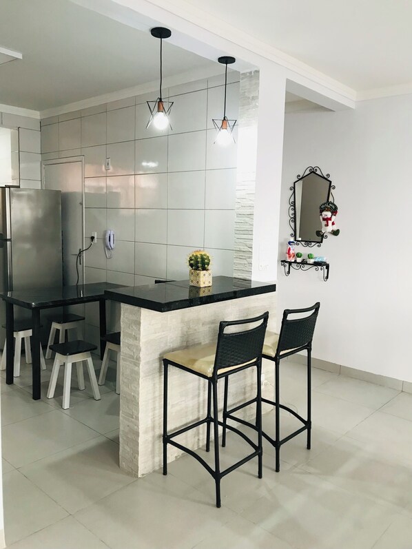 Una cocina moderna con una isla central, dos taburetes de bar e iluminación colgante.