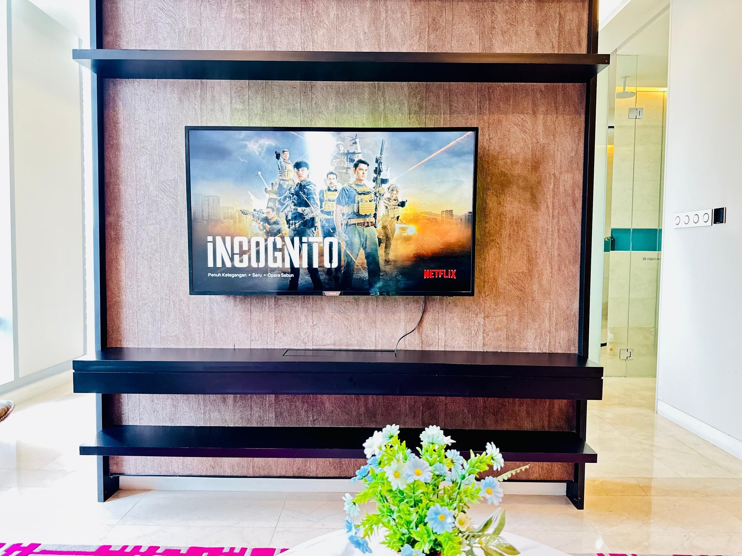 Et fjernsyn monteret på en trævæg, der viser en plakat fra Netflix.