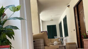 Uma área de estar aconchegante, com móveis de vime, um vaso colorido listrado e piso de azulejos.