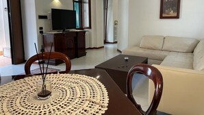 Uma sala de estar com sofá, mesa de centro, televisão e mesa de jantar com cadeiras.