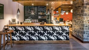 Eine Bar mit einer Holztresen, einer Tischdecke mit einem schwarzen Blumenmuster und einer Getränkekarte.