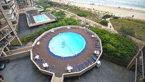 Una piscina en la azotea con tumbonas y vistas a la playa.