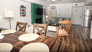 Un comedor con mesa de madera, sillas y televisor.