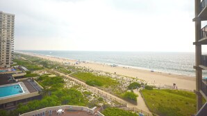 Vista de la playa desde un edificio alto con piscina y zona delimitada por vallas.
