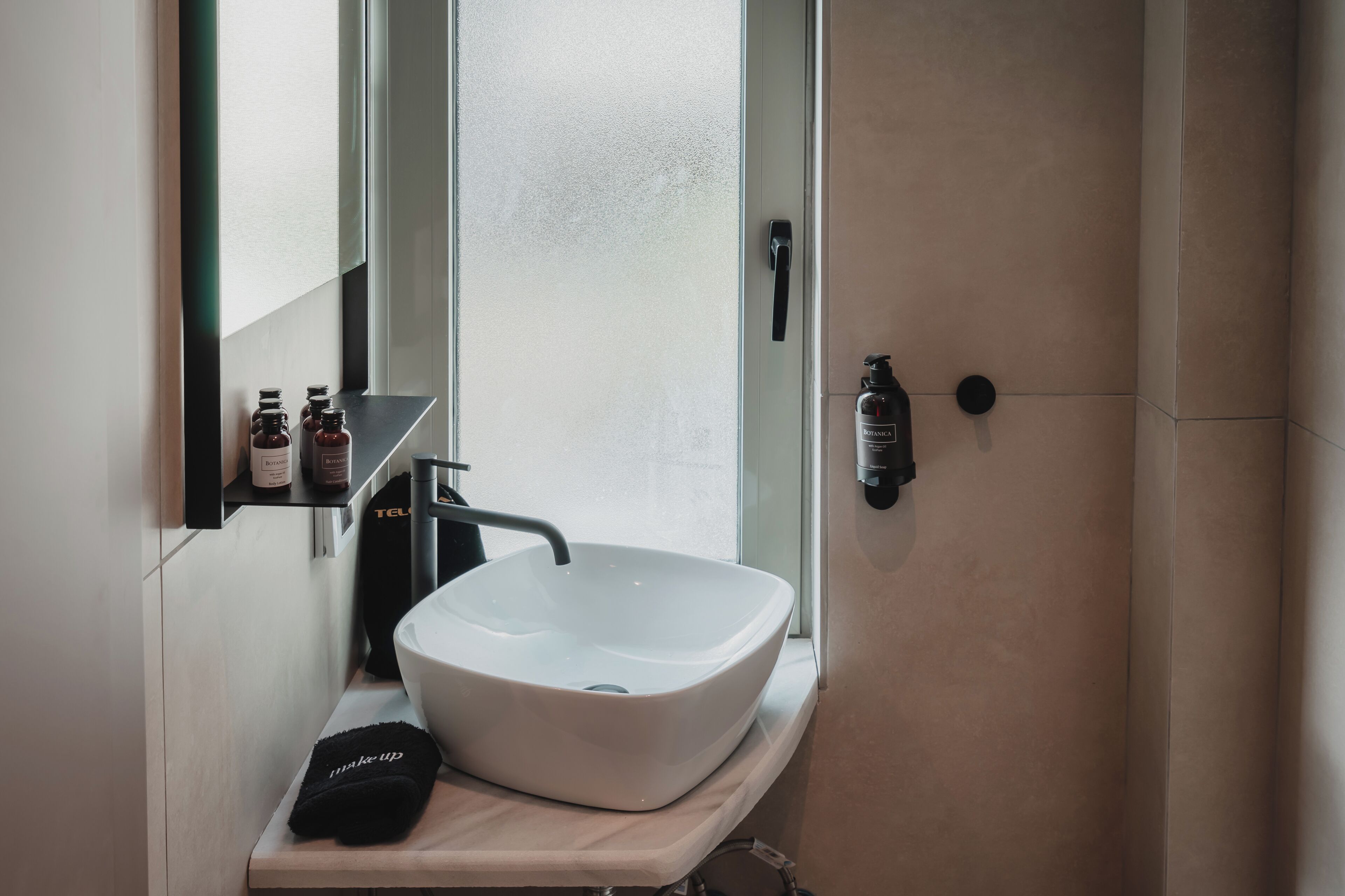 A bathroom with a white vessel sink, a black towel, and a mirror above it.