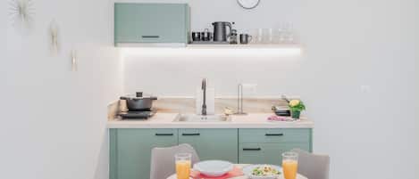 A modern kitchen with a sink, stove, and dining area with chairs and plates.