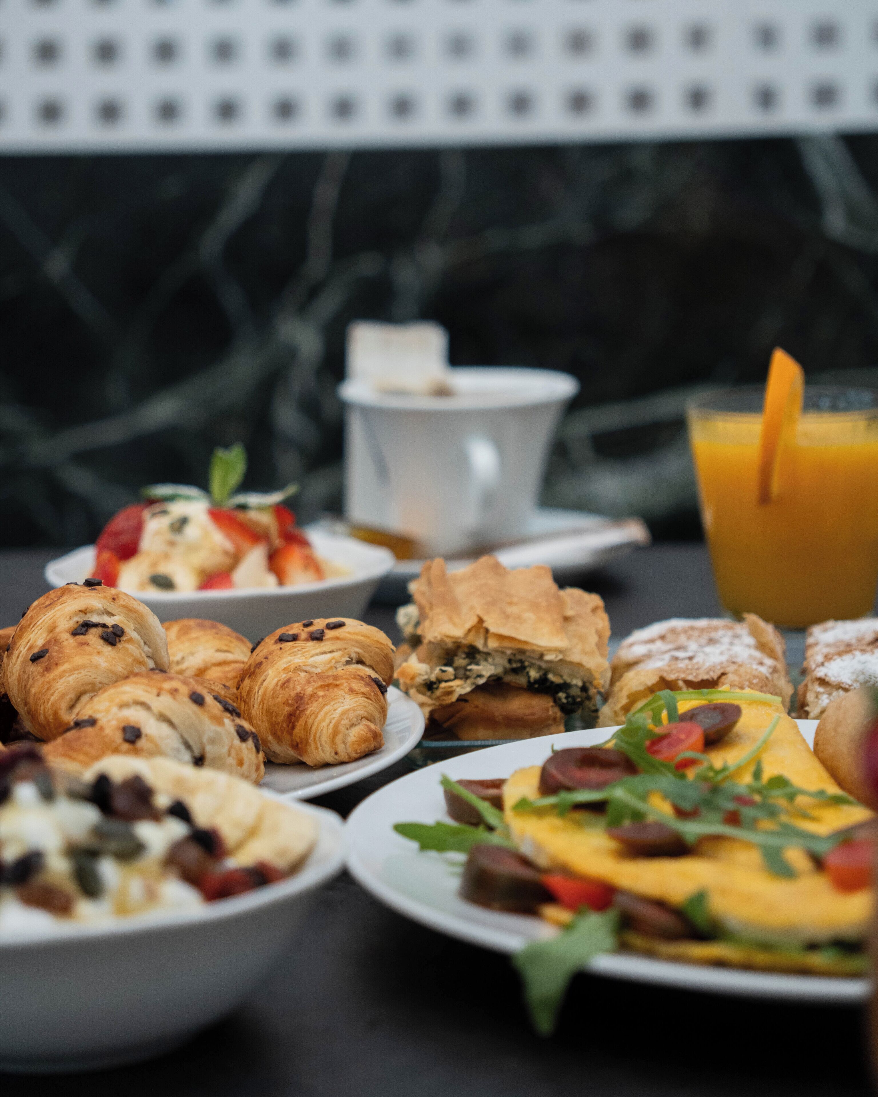 Un buffet de petit-déjeuner proposant un assortiment de viennoiseries, de sandwichs et un verre de jus d’orange.