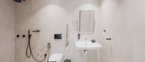A modern bathroom with a shower, toilet, and sink.