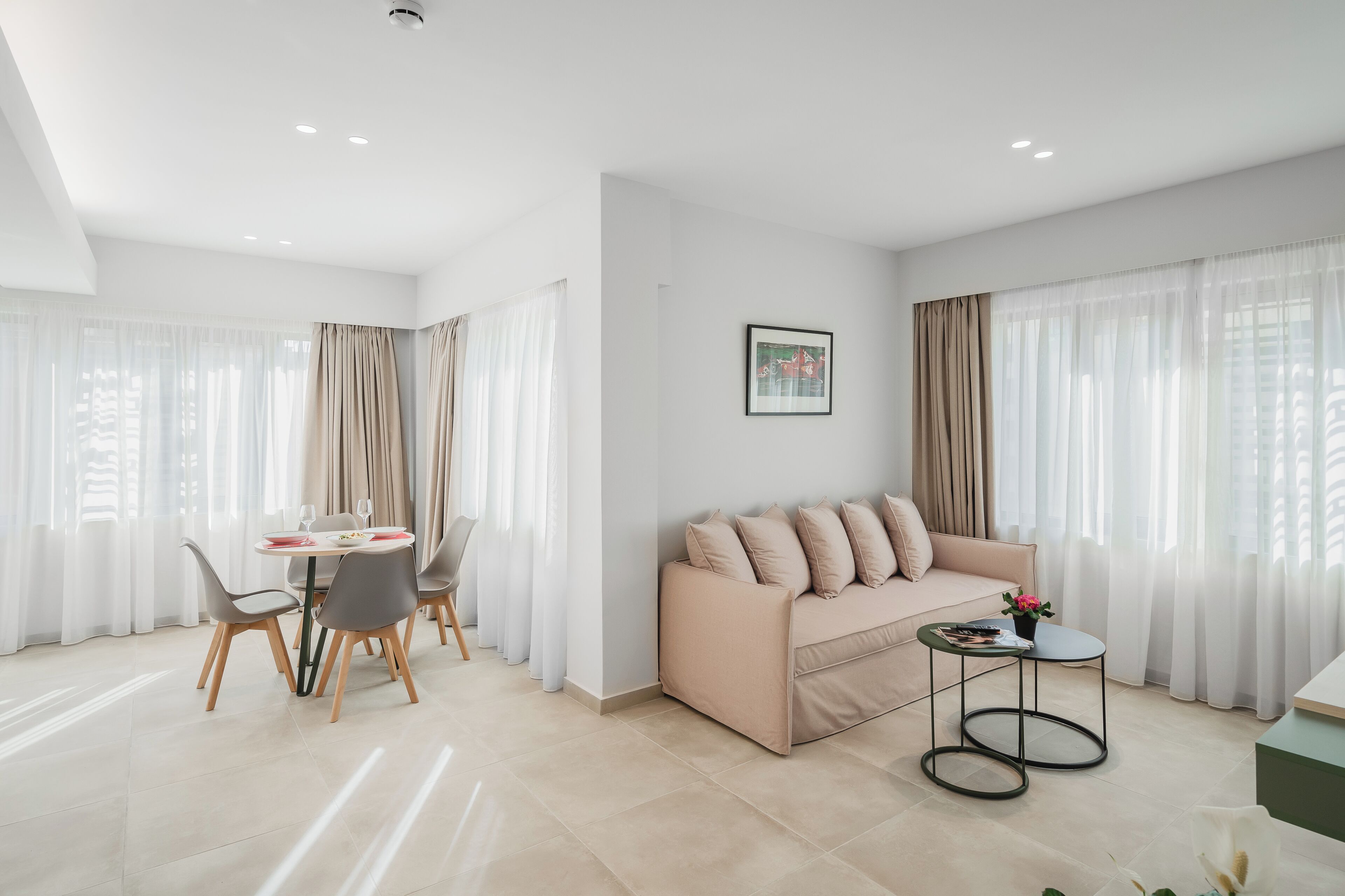 A modern living room with a beige sofa, a dining table with chairs, and a small side table.