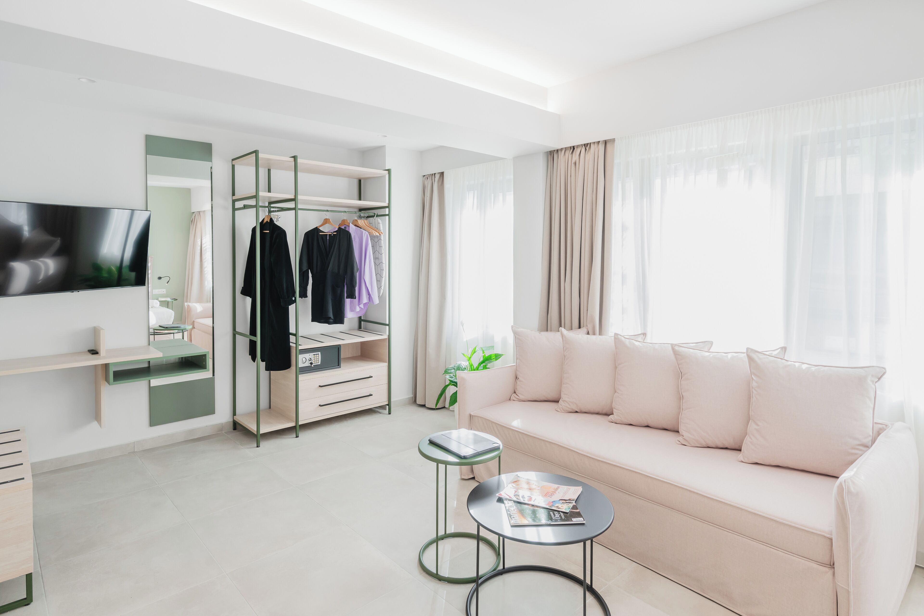 Un salon moderne comprenant un canapé, une table basse, un téléviseur, une armoire et un miroir.