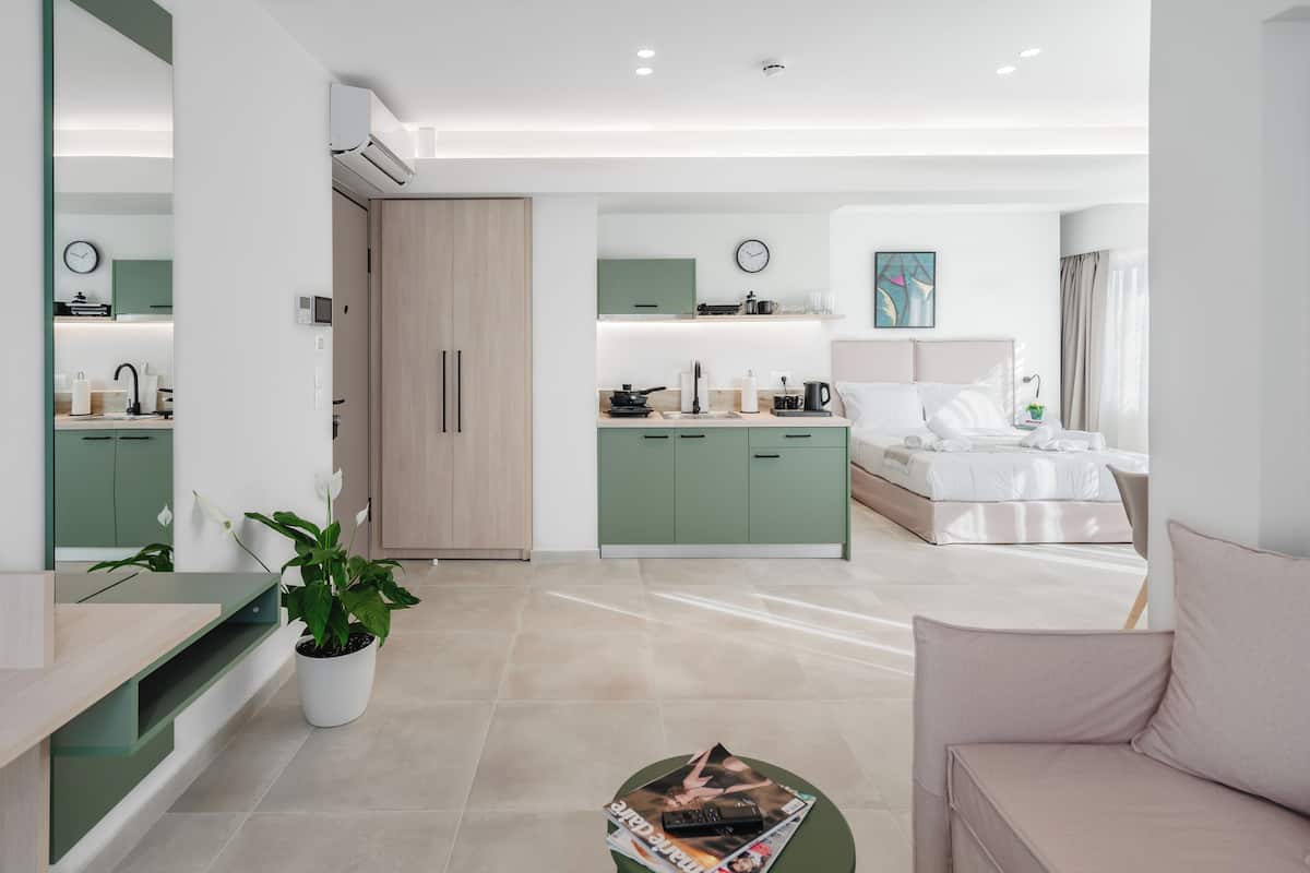 A modern hotel room with a kitchenette, a dining area, and a living space.