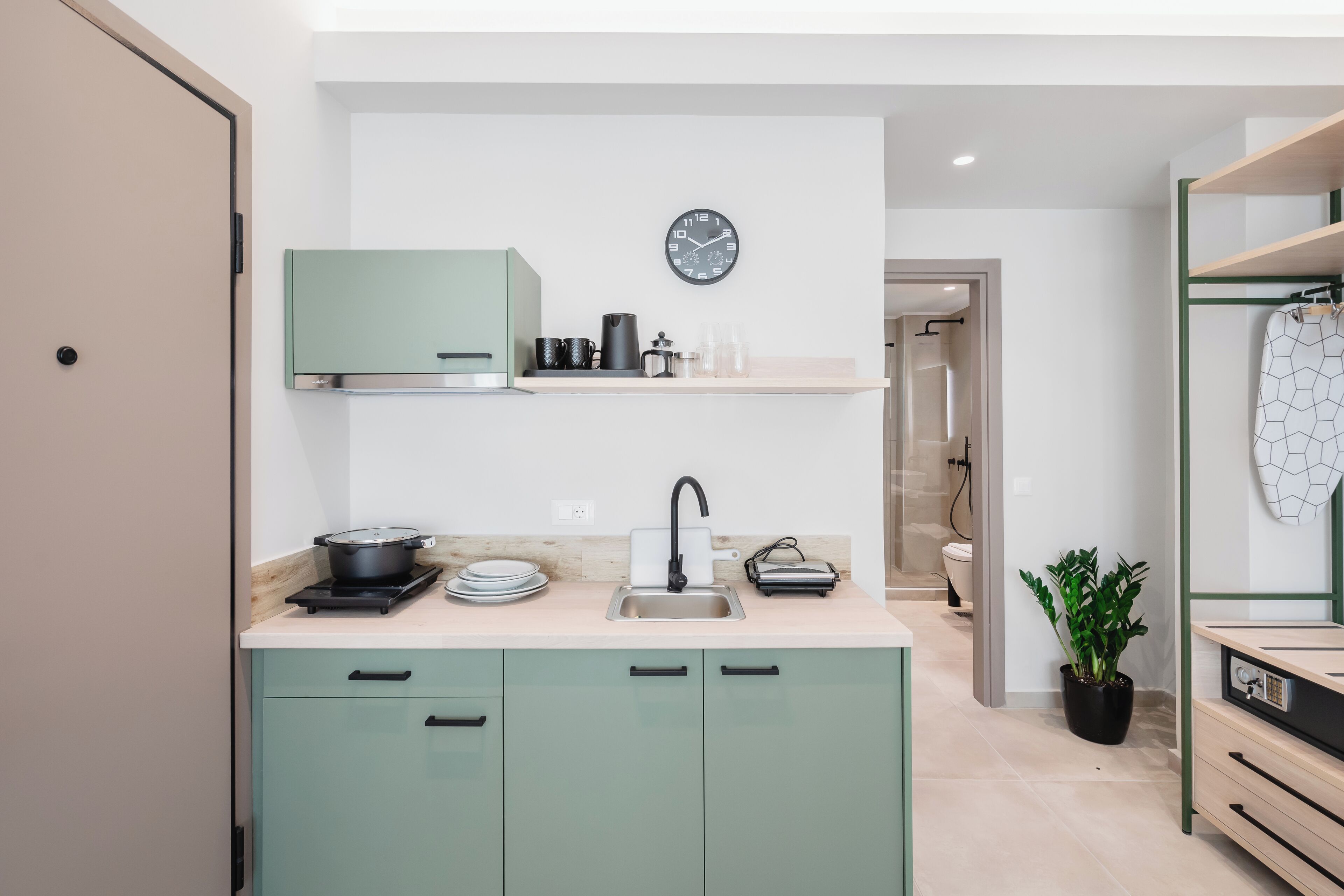 A modern kitchen with a sink, a stove, and a clock on the wall.