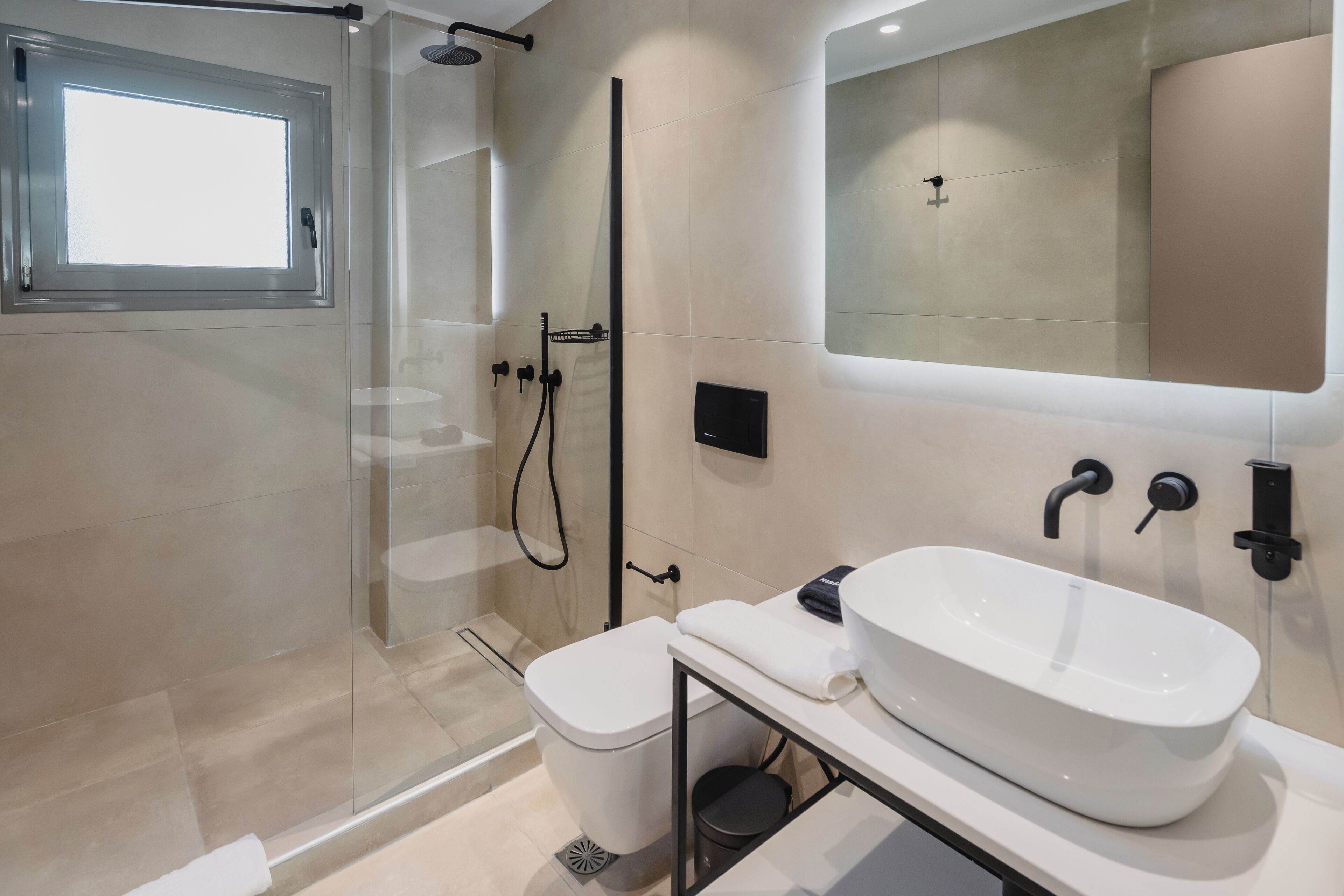 A modern bathroom with a glass-enclosed shower, a white sink, and a large mirror.