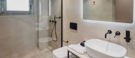 A modern bathroom with a glass-enclosed shower, a white sink, and a large mirror.