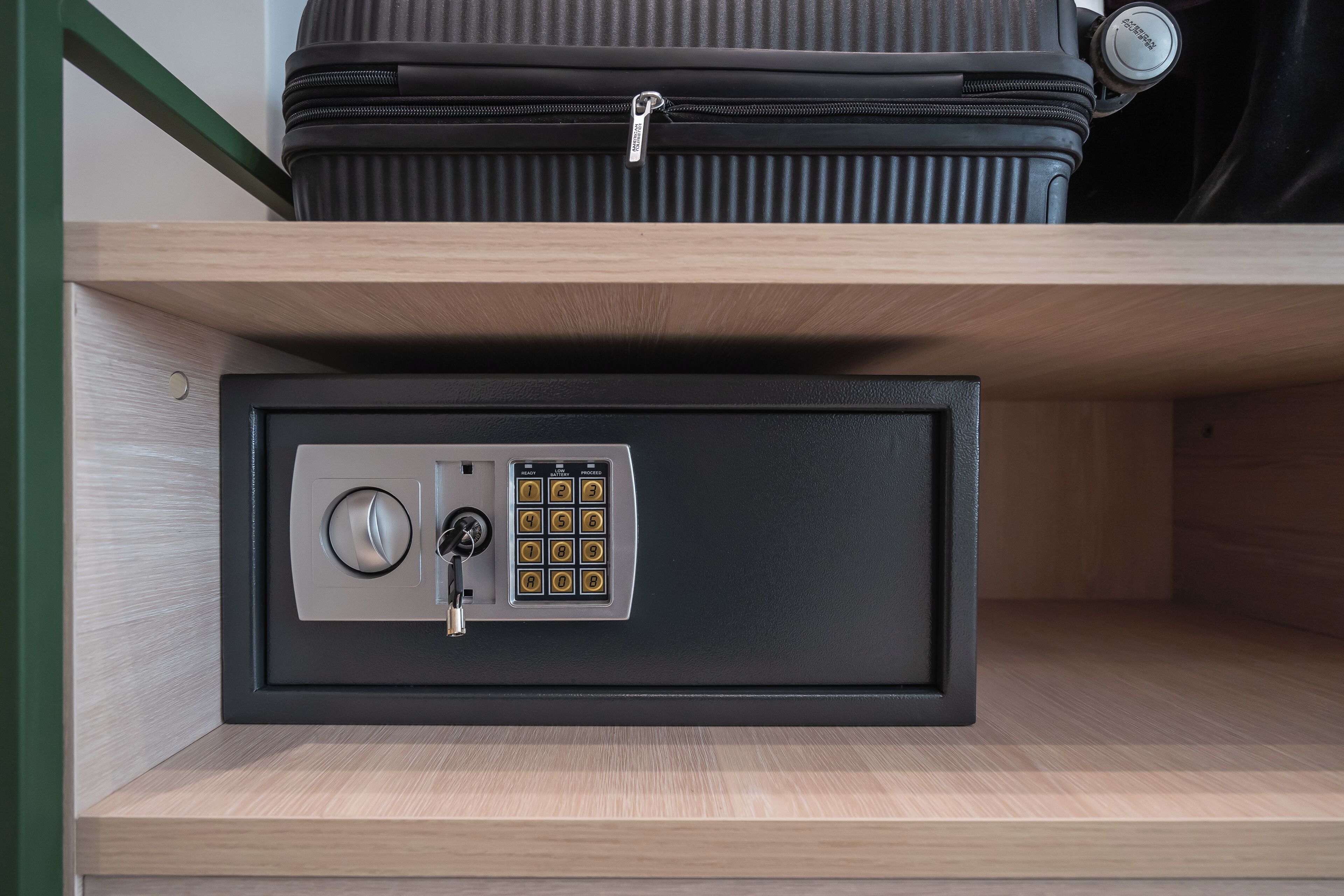 A secure safe with a combination lock and a keyhole, placed on a wooden shelf.