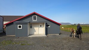 A small, single-story building with a red roof and a white door.