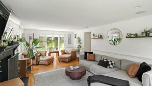 A spacious living room with a fireplace, a sofa, a coffee table, and a large mirror. - The Horseshoe Crib; Minutes to Beach & Downtown (Sandwich)
